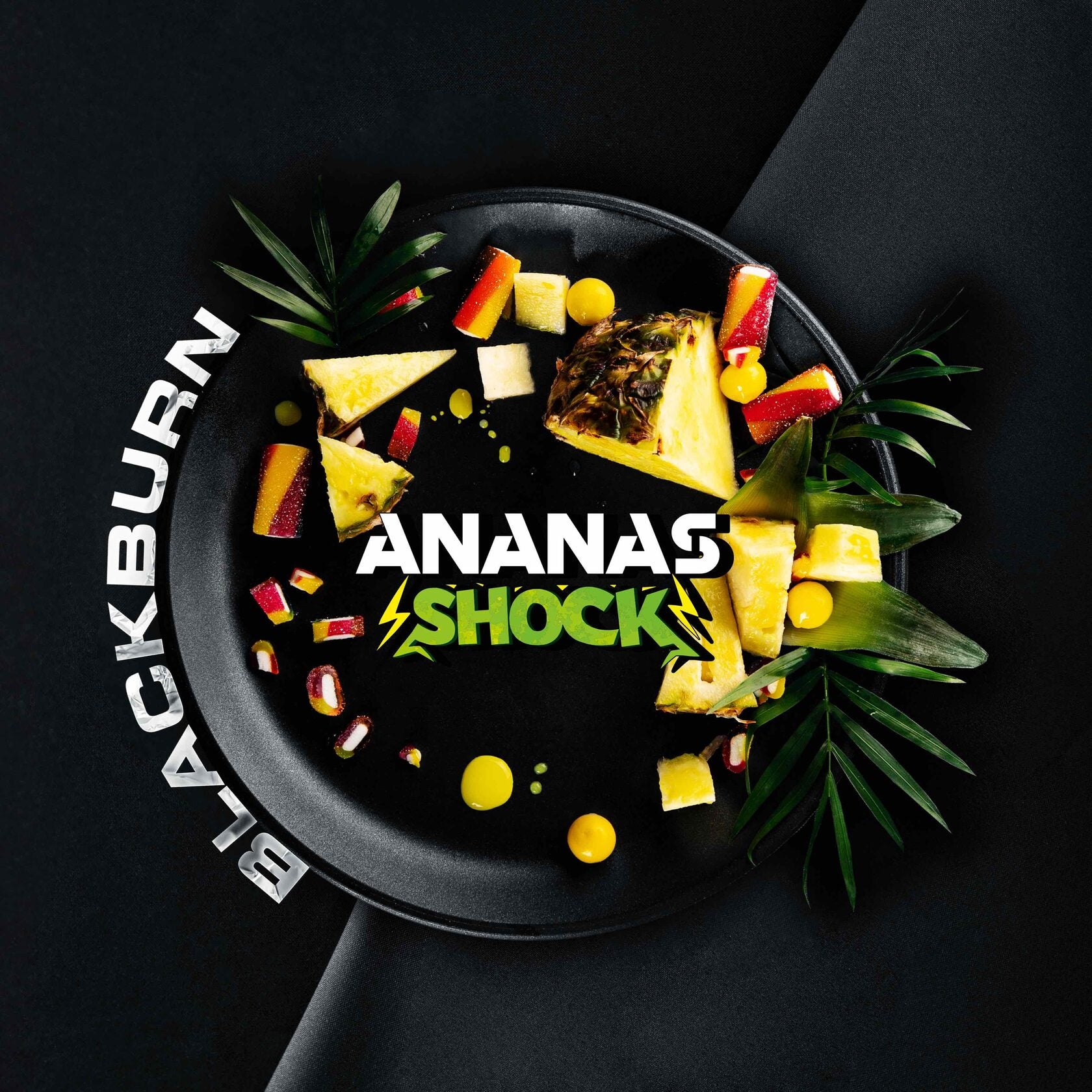 Black plate with sliced pineapple and red fruit pieces with Ananas Shock and Blackburn text