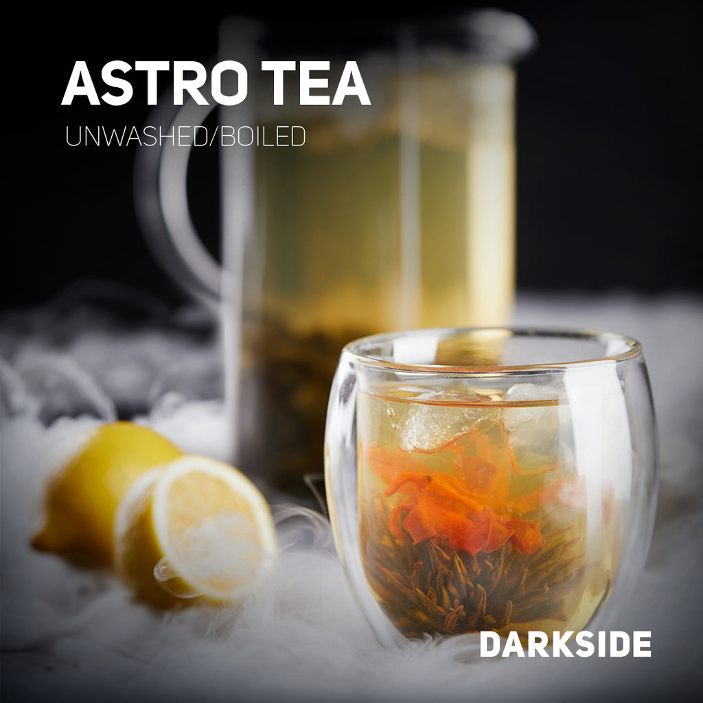 Clear glass cup of Astro Tea with flower petals and lemon slices on a smoky dark background