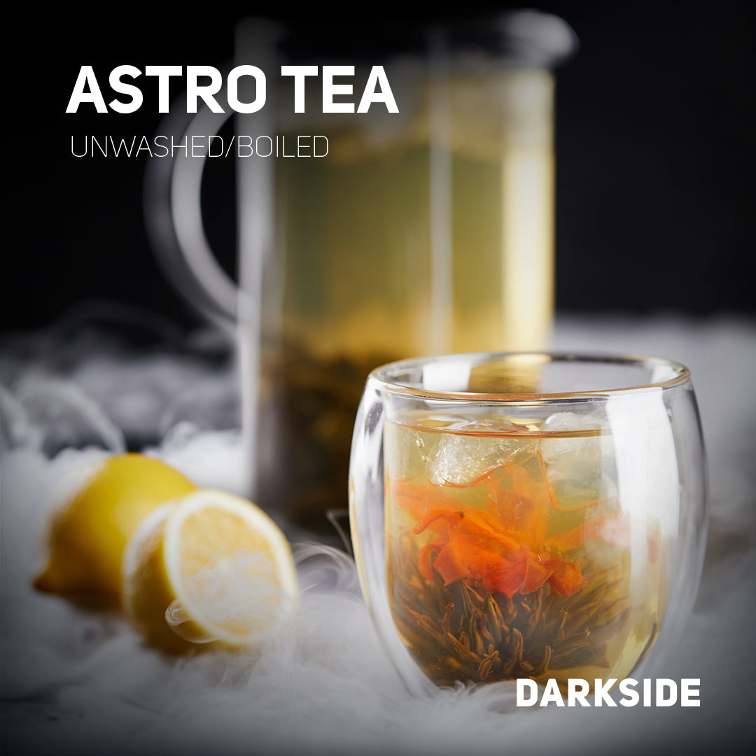 Clear glass cup of Astro Tea with flower petals and lemon slices on a smoky dark background