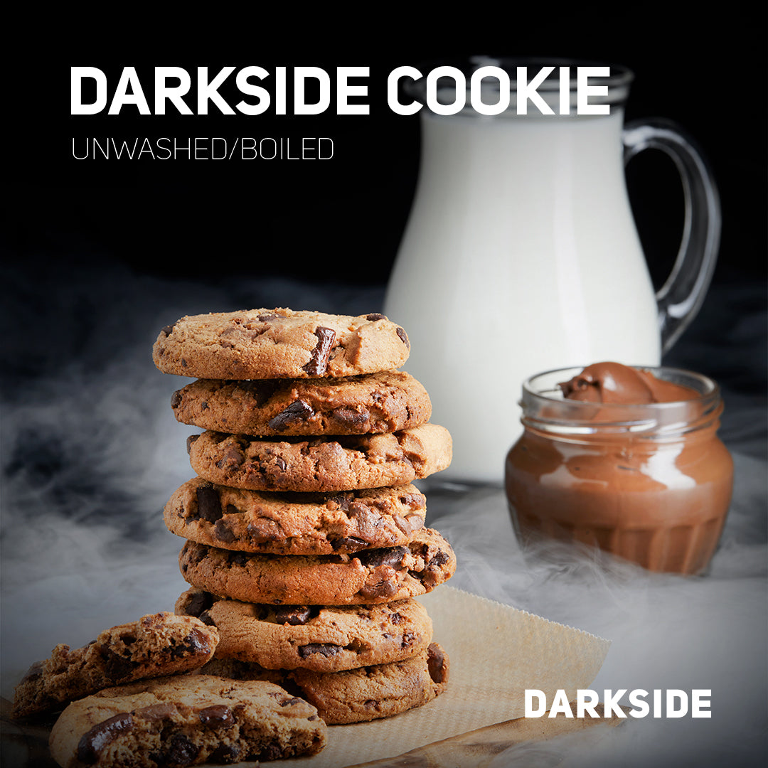 Stack of Darkside Cookie chocolate chip cookies with milk pitcher and jar of chocolate spread in background